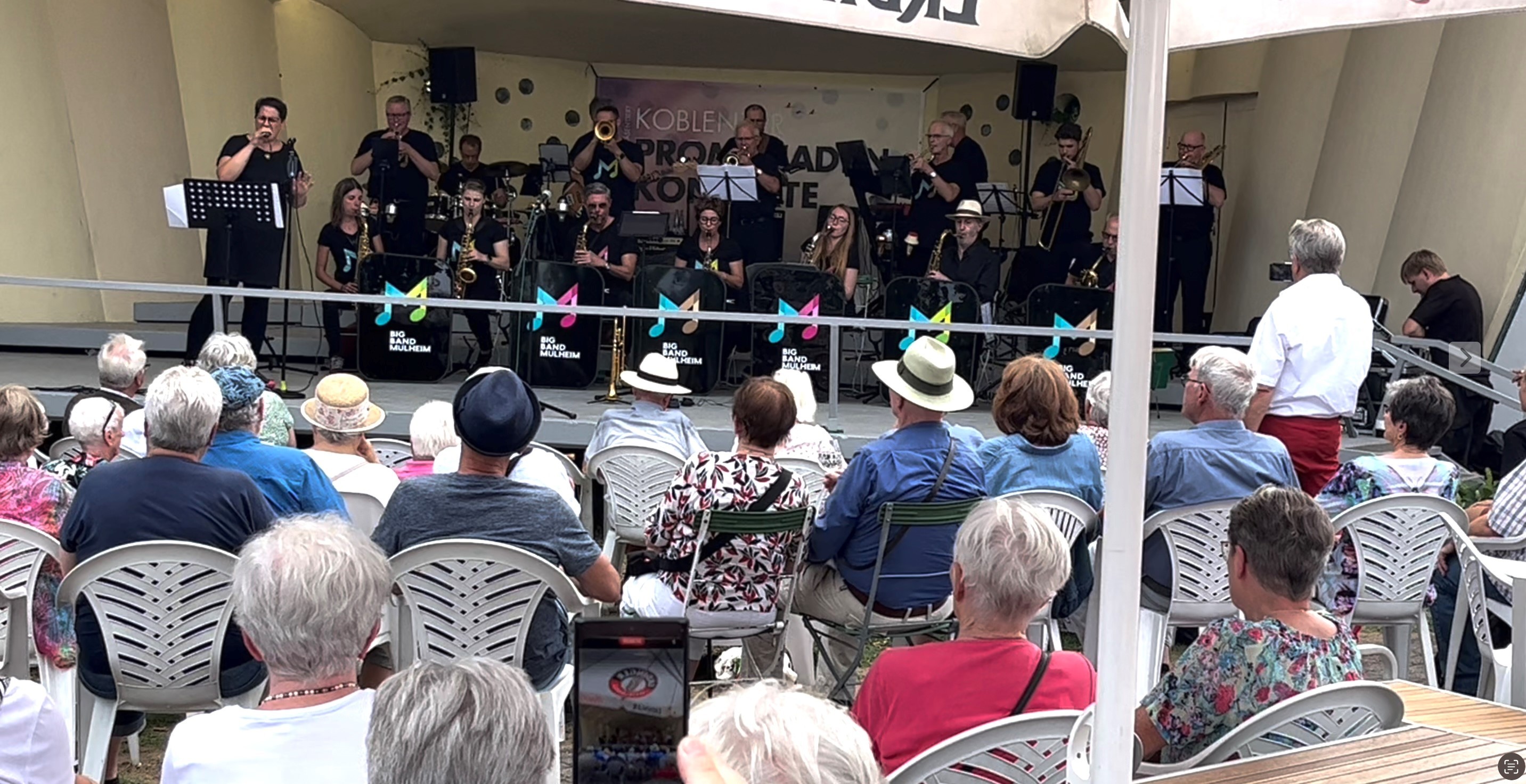 Zuschauer sitzen vor der bespielten Konzertmuschel in den Koblenzer Rheinanlagen